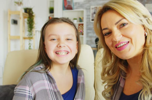 Mom and daughter with braces, smiling. 